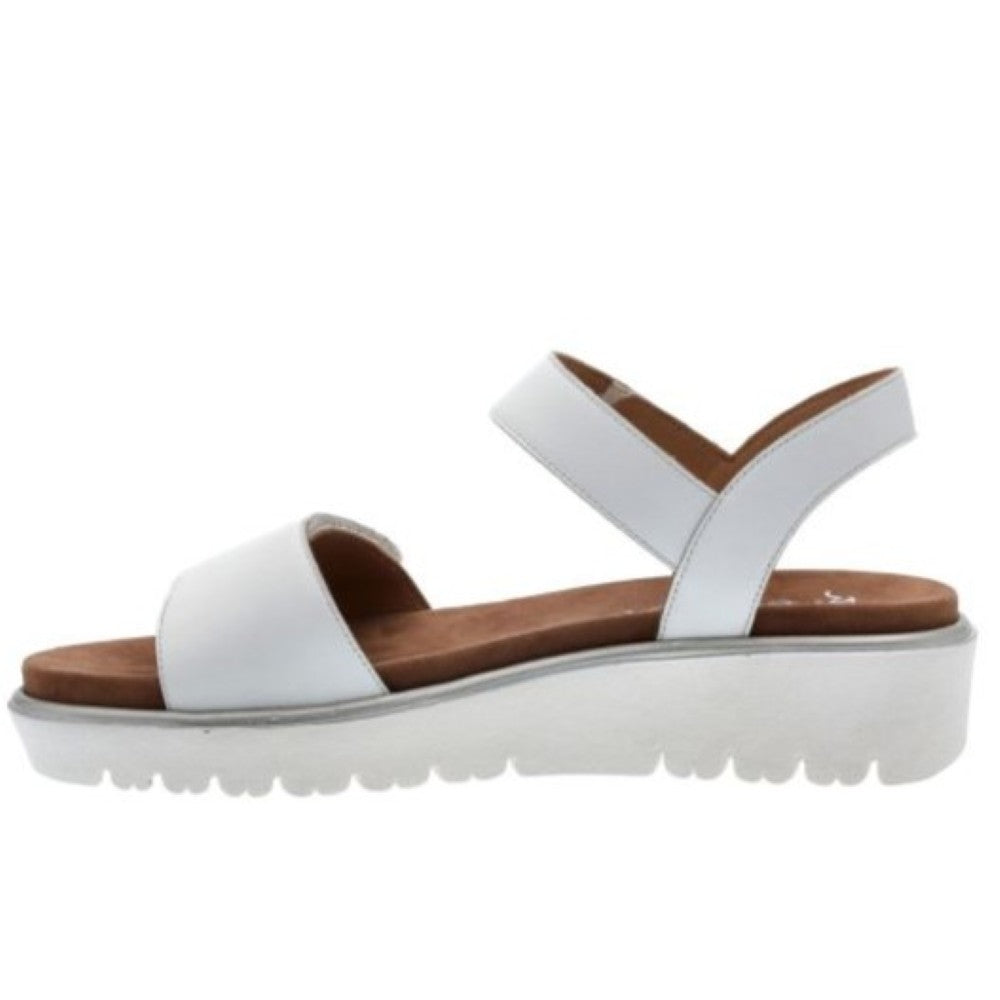 A white leather platform sandal with a wide front strap and a single adjustable ankle strap, featuring a brown footbed and a chunky white sole with a textured tread.