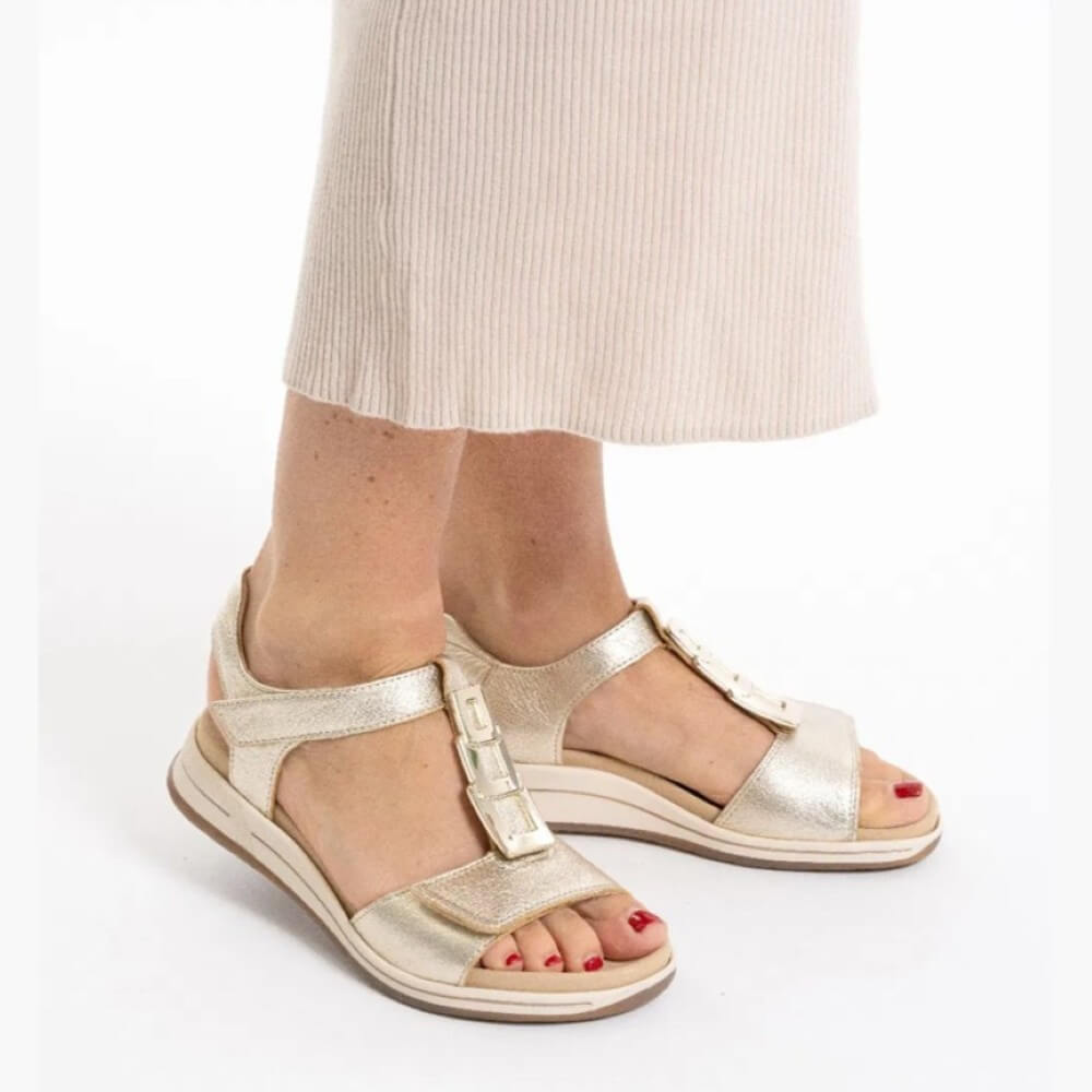 ara Gold sandals worn with beige pants on a white background