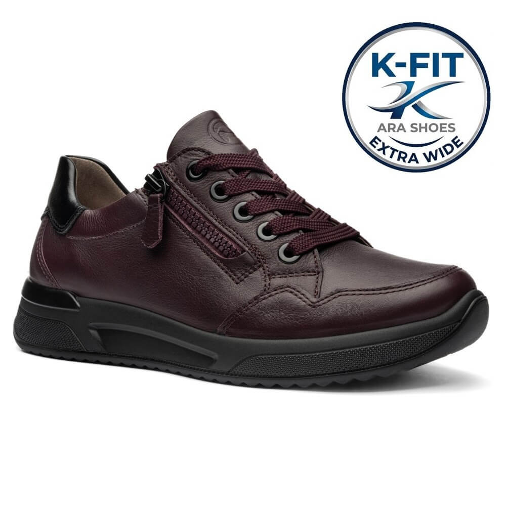 Ara dark burgundy leather low-top shoe with a black sole,  on a white background. A circular blue and white 'K-FIT ARA SHOES EXTRA WIDE' logo badge is positioned in the top right corner.