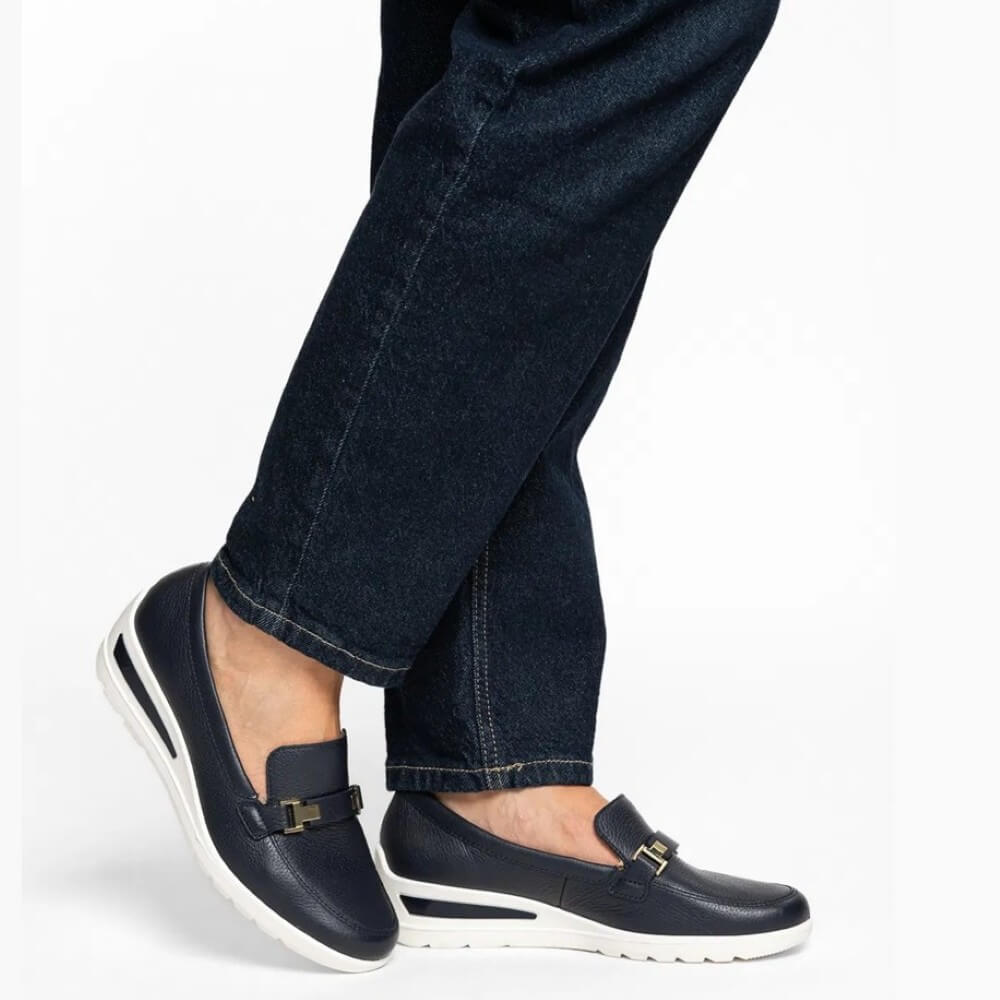 Navy loafers worn with dark jeans on a white background