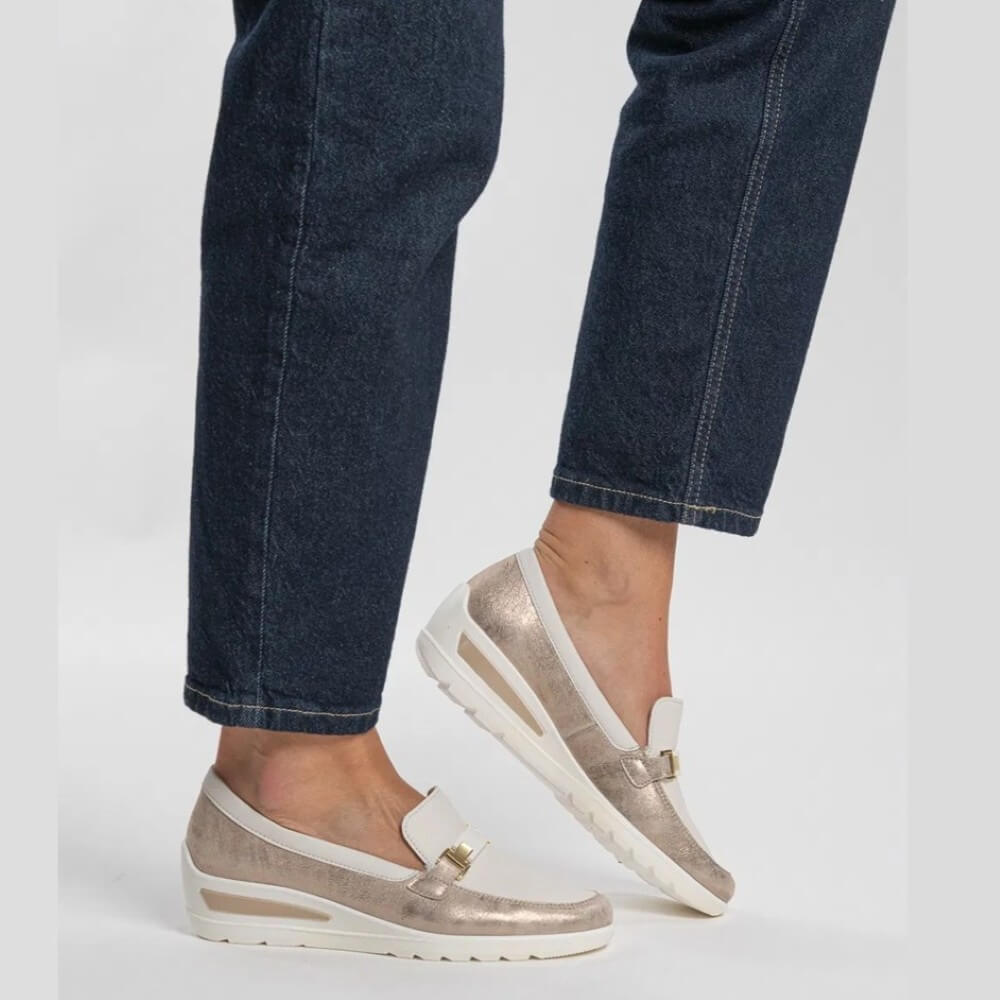 beige and cream loafers worn with blue jeans on a light gray background