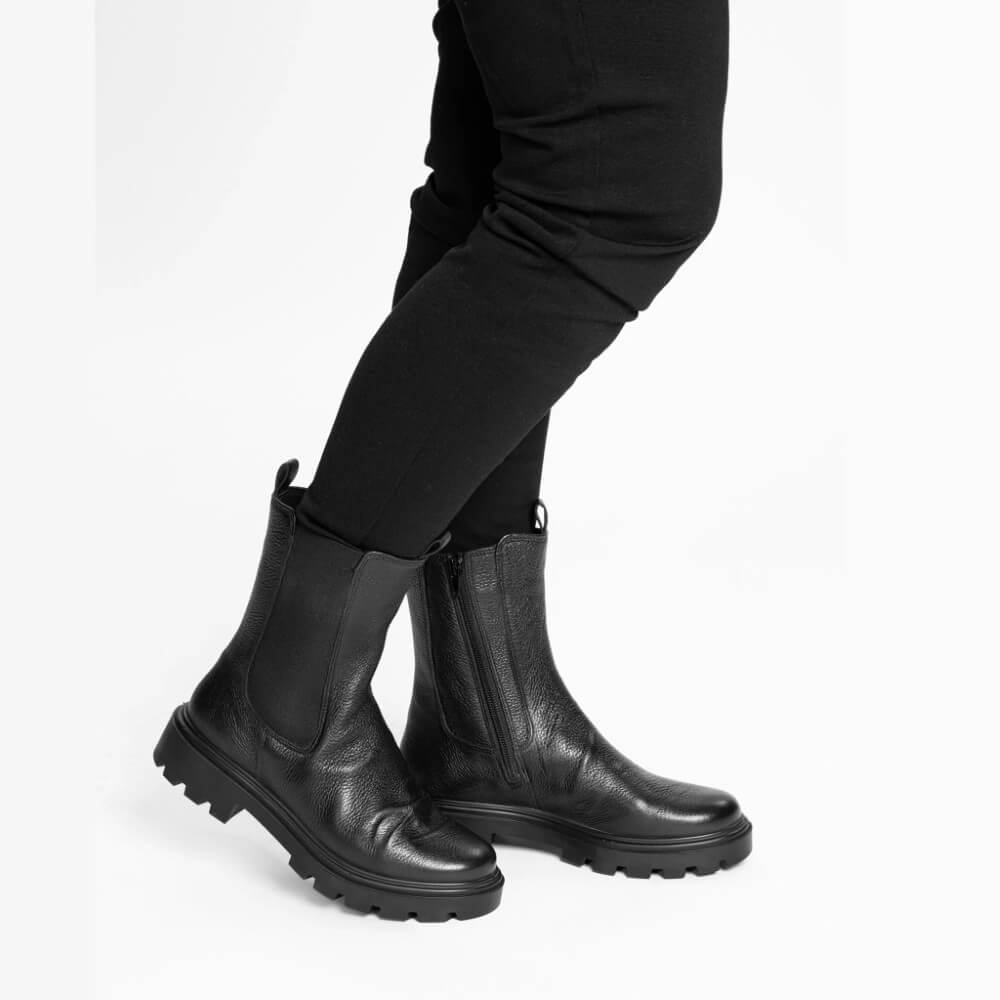 Black rubber boots worn with black pants on a white background