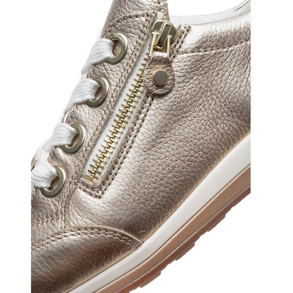Close-up of a metallic sneaker with a gold zipper on a white background