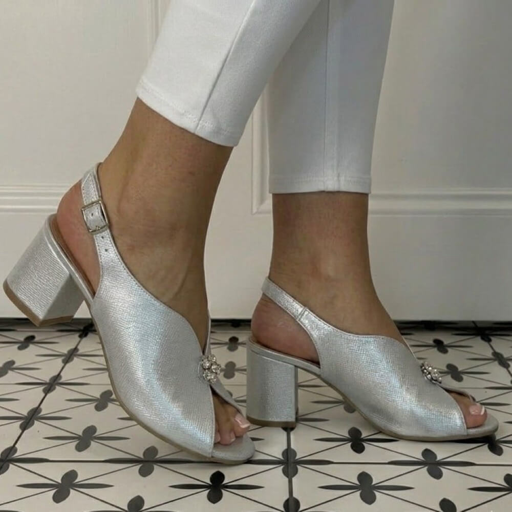 Bioeco Silver open-toe high-heeled shoes with decorative elements on a patterned floor.