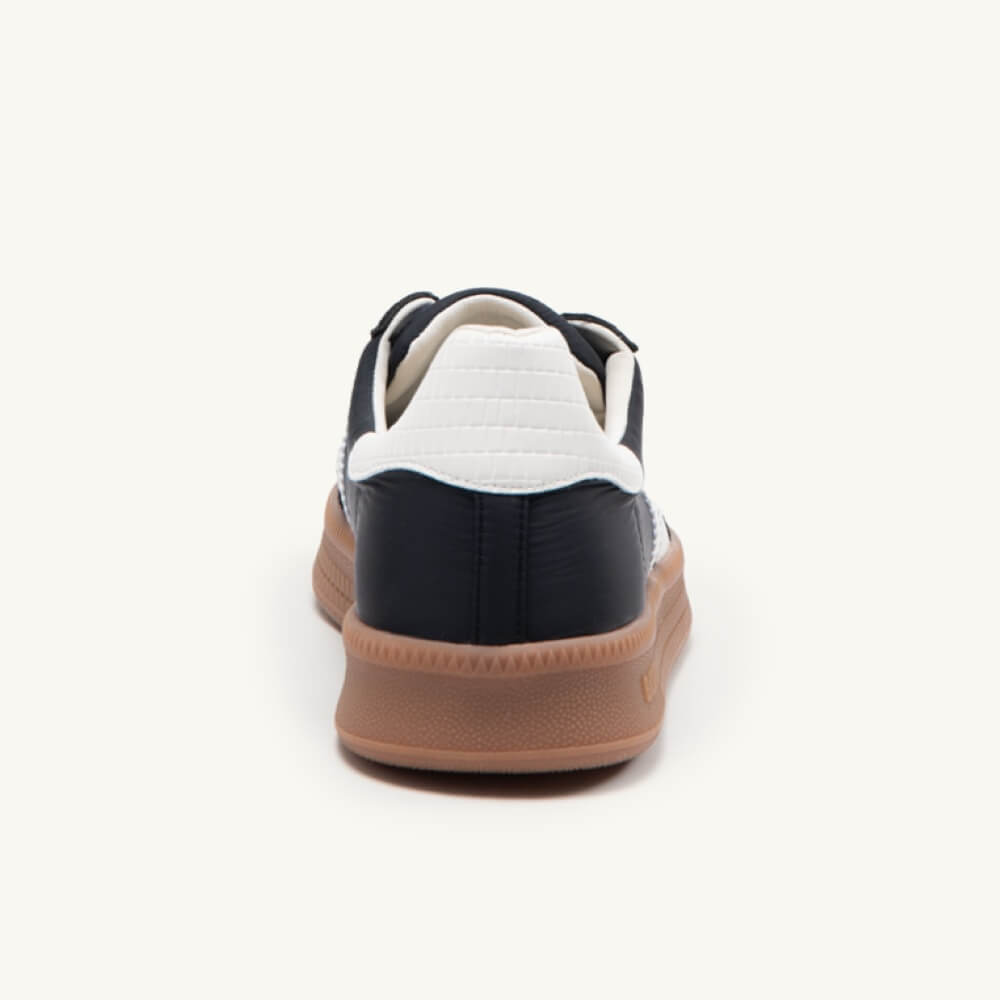 Black and white sneaker with brown sole on a white background