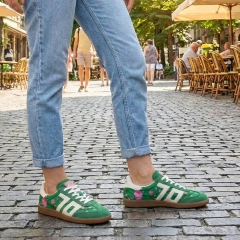 Back 70 Green sneakers with floral designs worn on a cobblestone street.