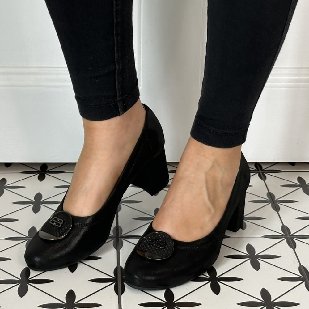 Black high-heeled shoes worn with black pants on a patterned floor. Bioeco 6844 Block Heel Black Shimmer Suede court shoes