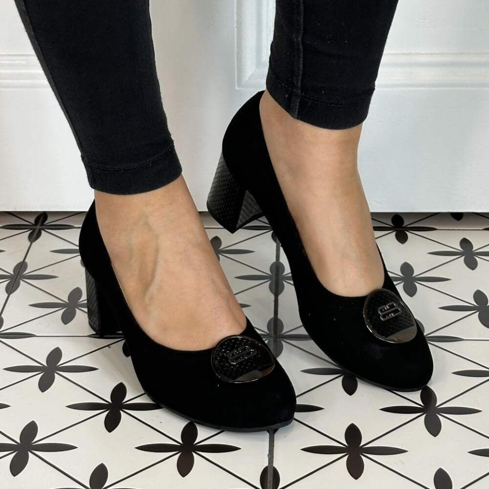 Black high-heeled shoes worn with black pants on a patterned floor. Bioeco 6844 Block Heel Black Suede court shoe