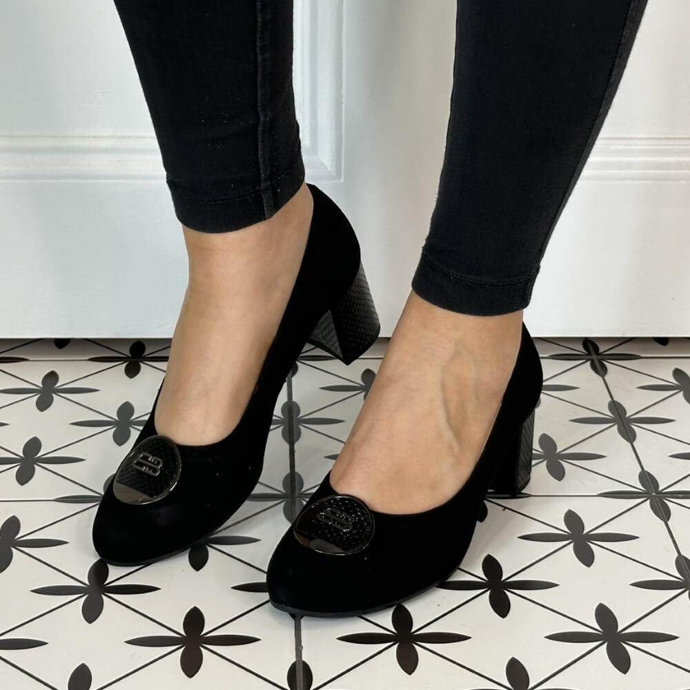 Black high-heeled shoes worn with black pants on a patterned floor. Bioeco 6844 Block Heel Black Suede court shoe