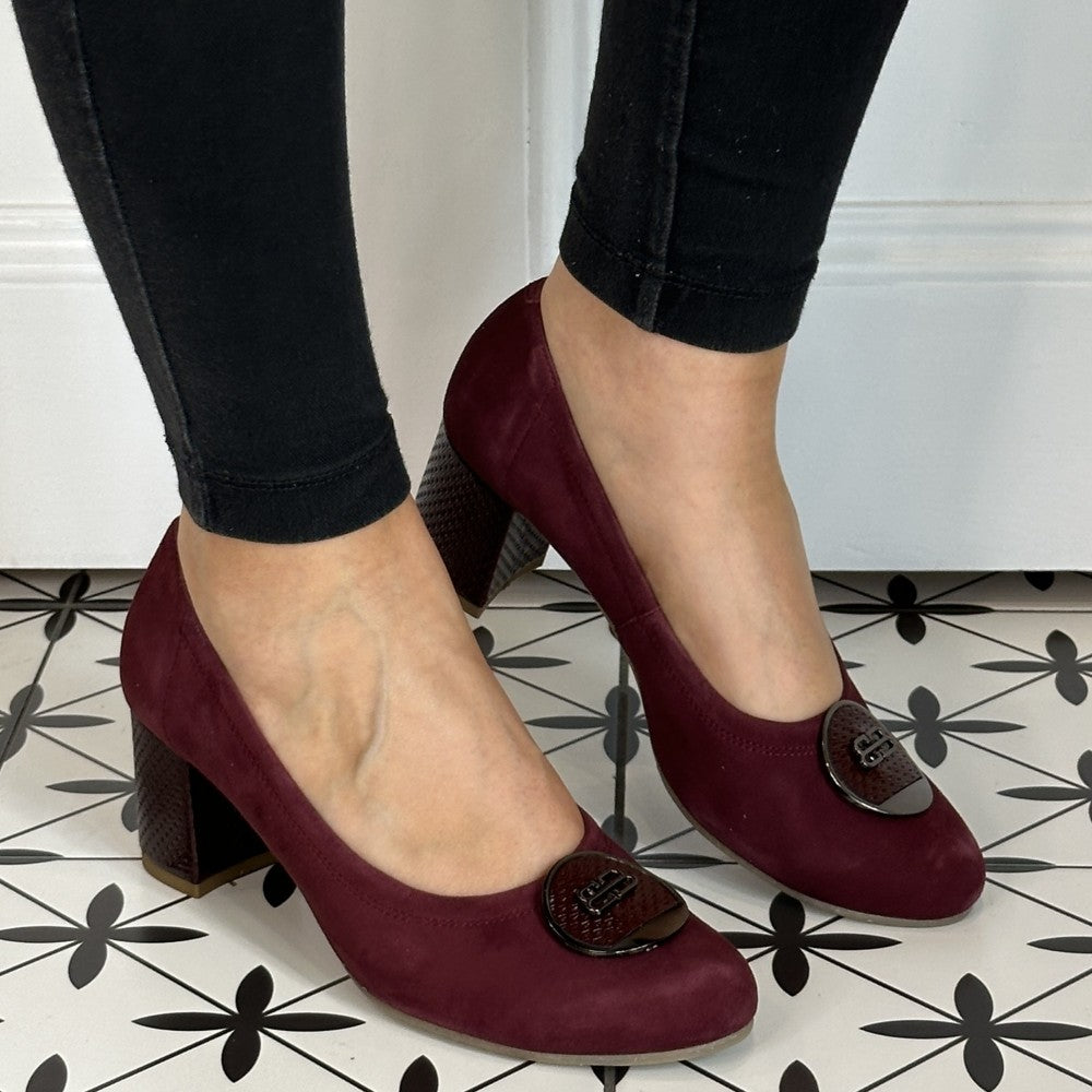 Wine high-heeled shoes worn with black pants on a patterned floor. Bioeco 6844 Block Heel Burgundy Suede