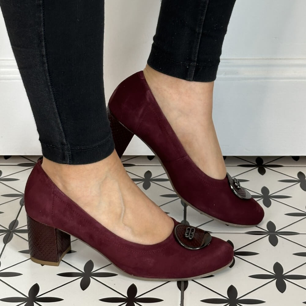 Wine high-heeled shoes worn with black pants on a patterned floor. Bioeco 6844 Block Heel Burgundy Suede
