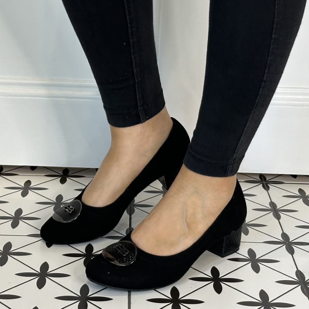 Black high-heeled shoes with floral embellishments worn with black pants on a patterned floor. Bioeco 6861 Low Block Heel Black Suede court shoes
