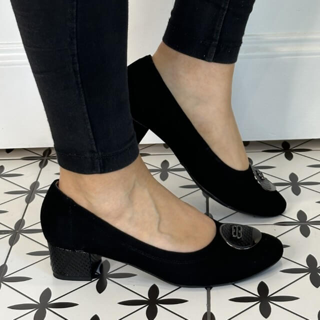 Black low heel shoes worn with black pants on a patterned floor. Bioeco 6861 Low Block Heel Black Suede court shoes