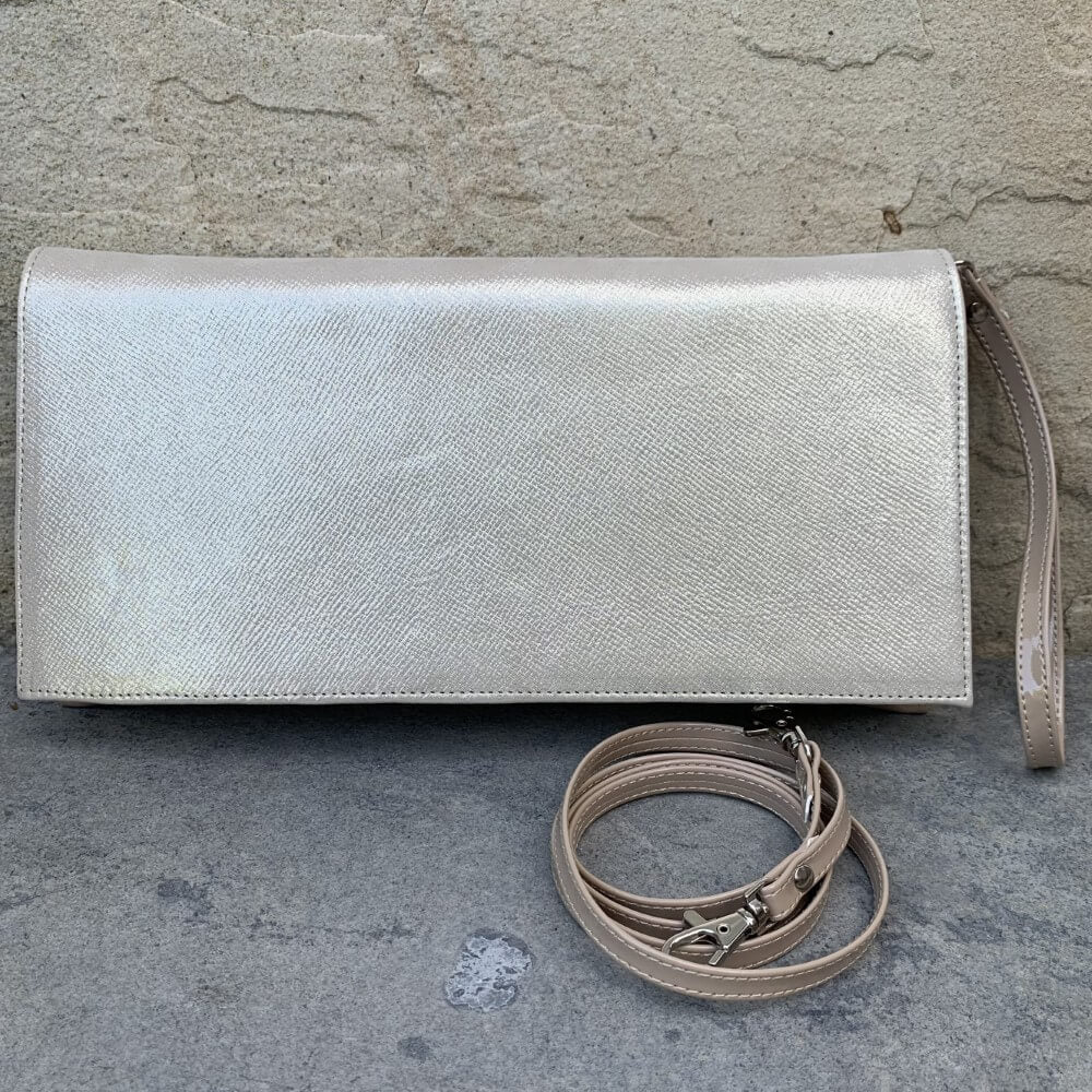 gold clutch bag with a strap on a concrete surface