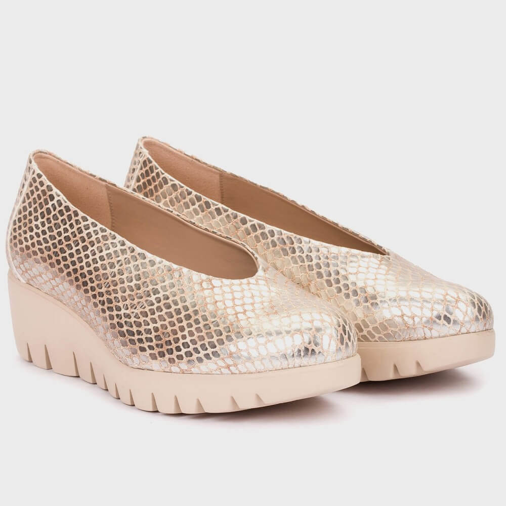 Pair of gold wedge shoes on a light gray background