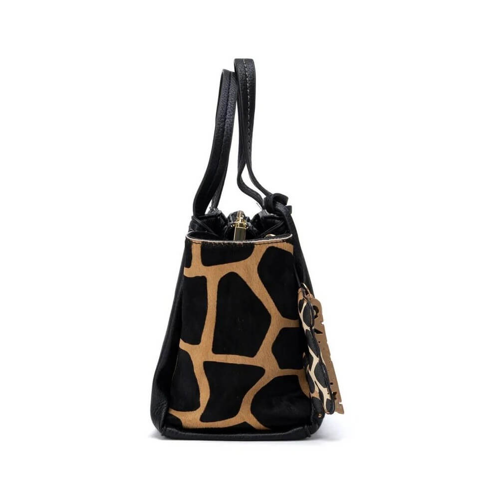 A Carmela small black and tan giraffe-print bucket bag with a single shoulder strap and a hanging leather keychain, shown against a plain white background.