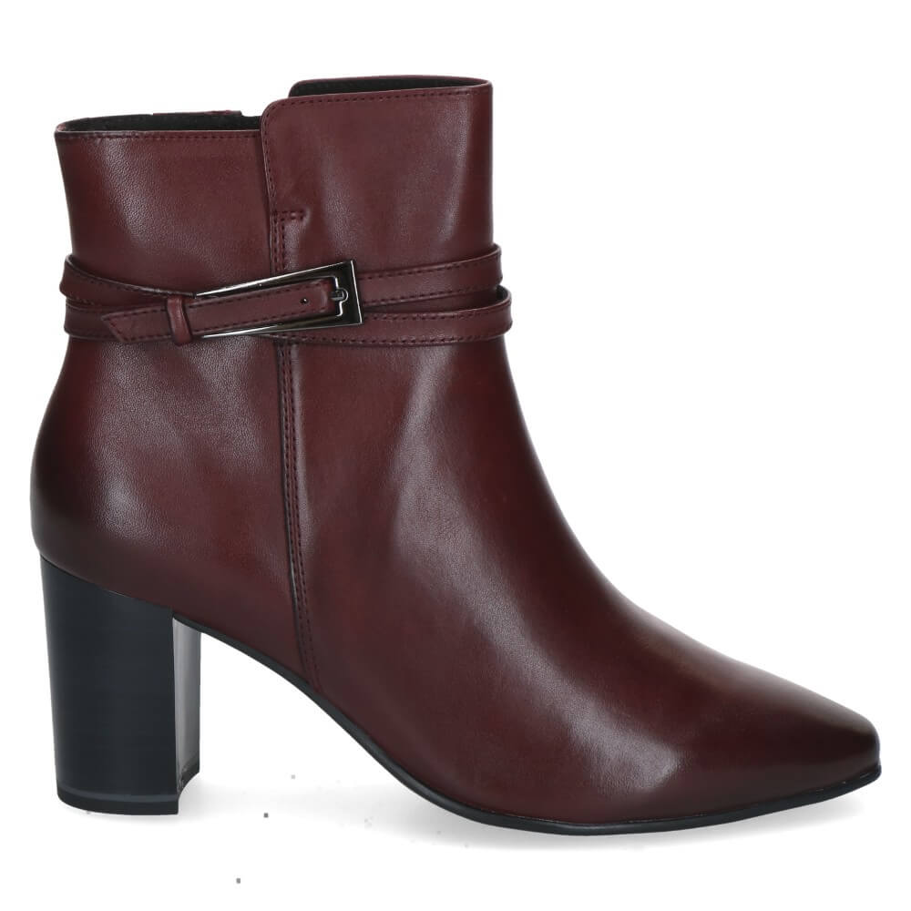 A Caprice wine leather ankle boot with a block heel, pointed toe, and a decorative strap with a buckle detail around the ankle.