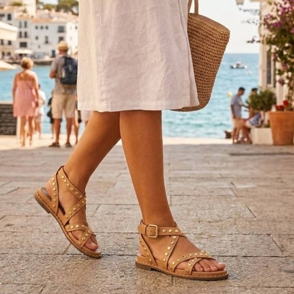 Person wearing tan sandals with a beach and ocean view in the background