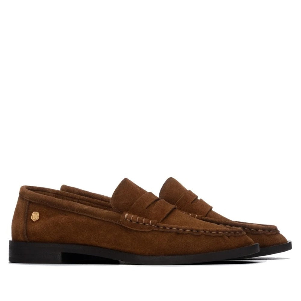 A pair of Carmela brown suede penny loafers with a black sole, shown from a side profile view against a plain white background.