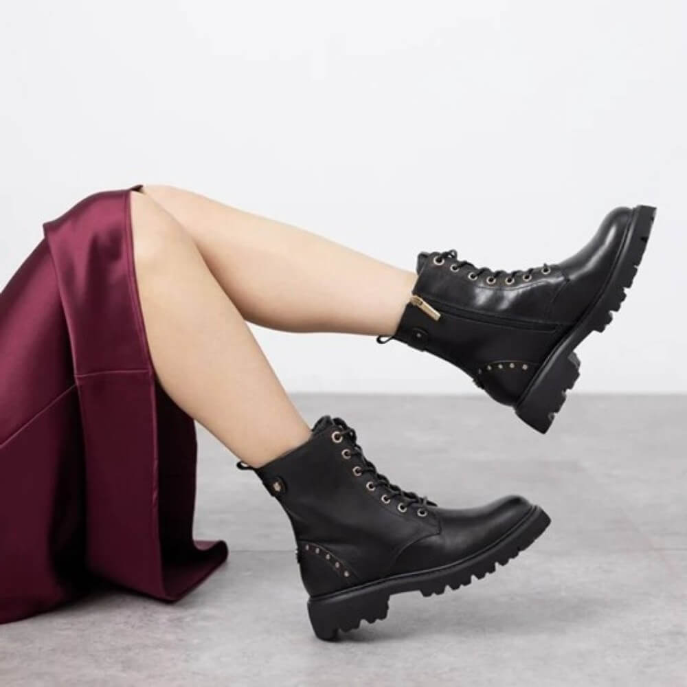 person wearing black leather boots and a wine dress