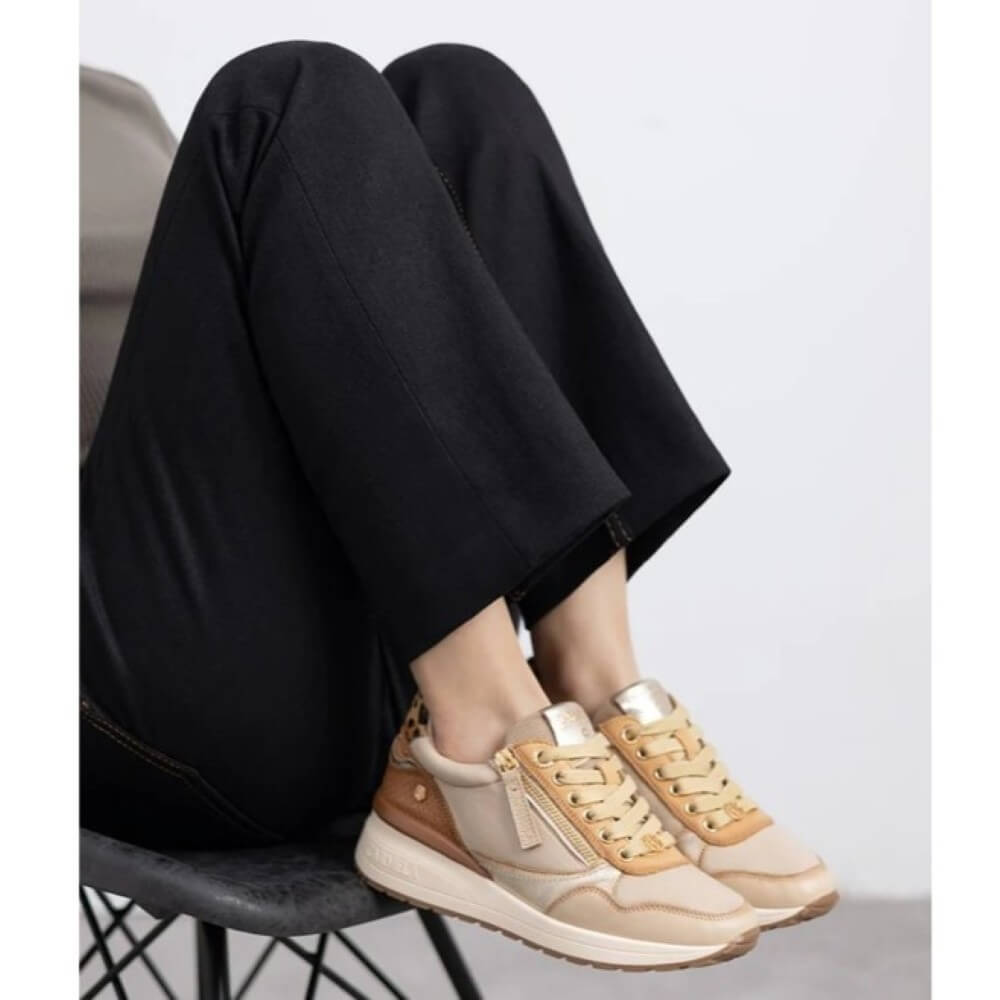 Person wearing beige sneakers with black pants sitting on a chair. Carmela Leather Sneakers 162442 