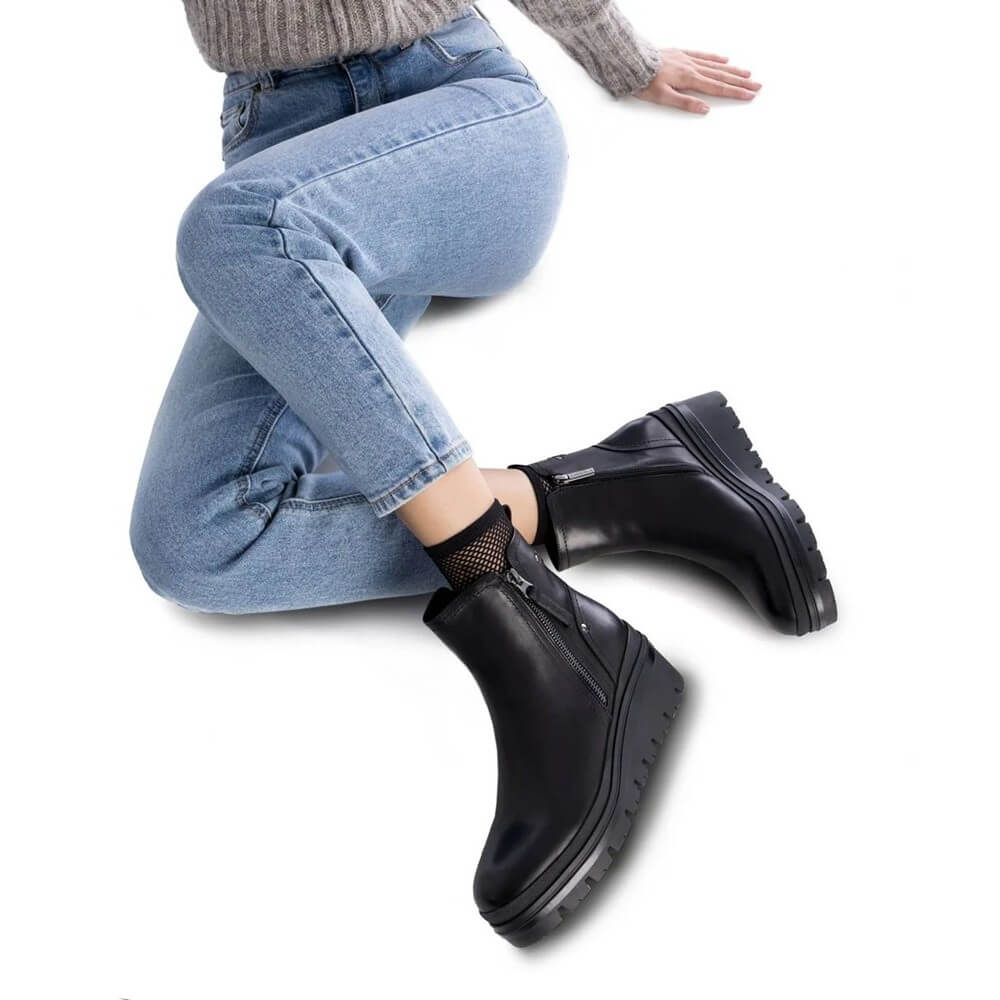 Woman wearing black leather ankle boots and jeans