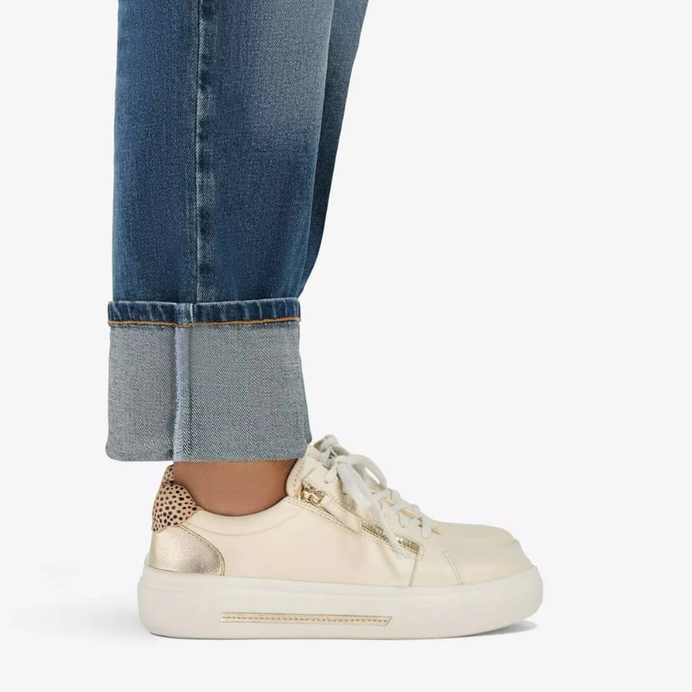 Person wearing Clarks Cream Leather sneaker with leopard print details on a white background