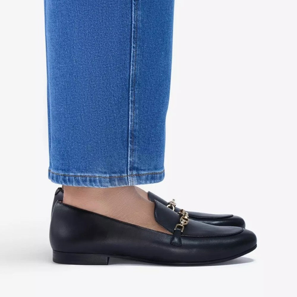 Clarks Black loafers with gold chain detail worn with blue jeans on a white background