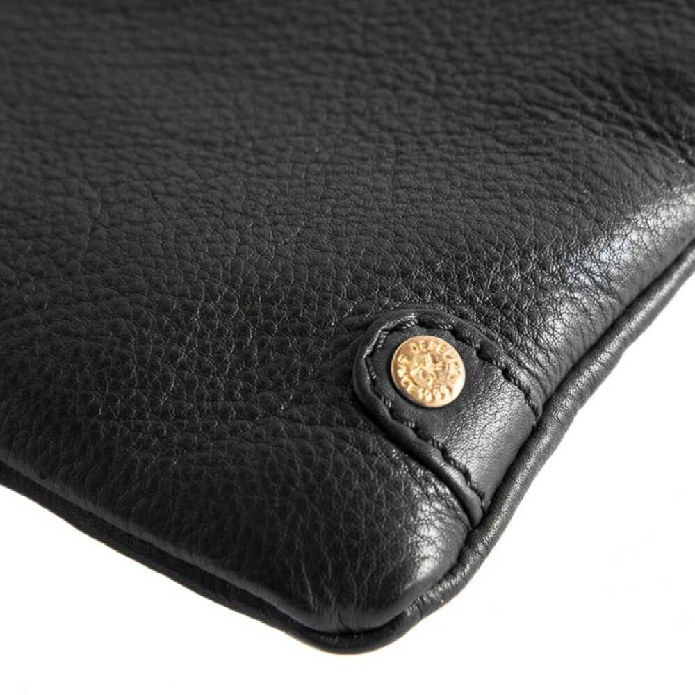 Close-up of a Depeche black leather bag with a gold button on a white background