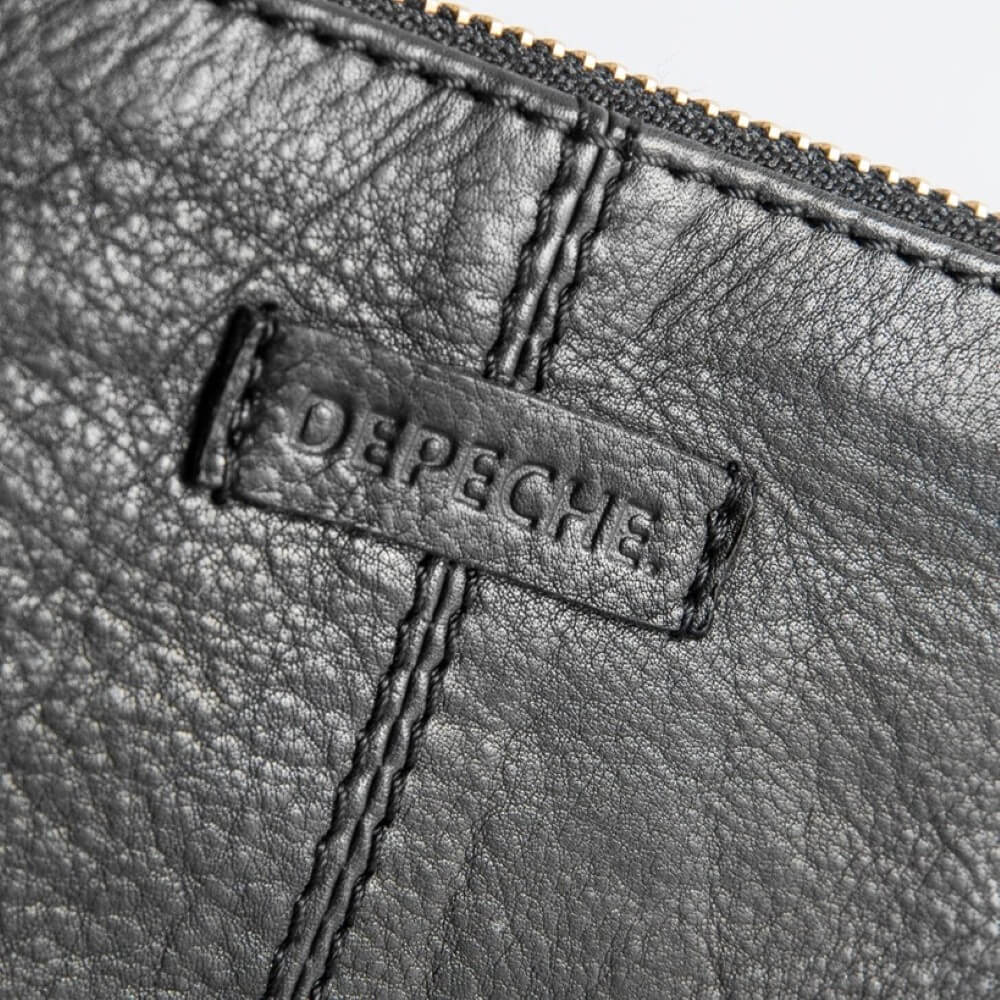 Close-up of a leather pouch with 'Depeche' branding on a gray background