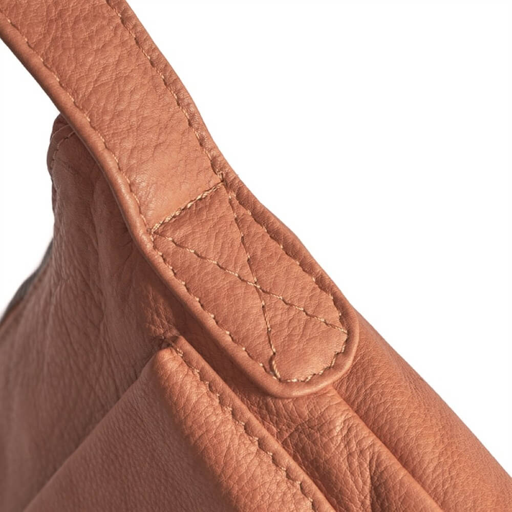 Close-up of a brown leather crossbody with a textured handle on a white background