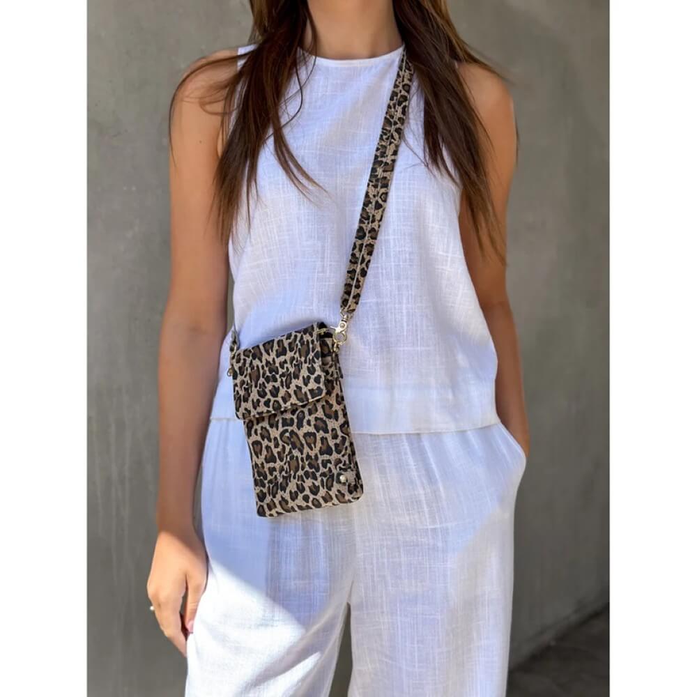 Person wearing a white outfit with a Depeche leopard print crossbody bag against a neutral background