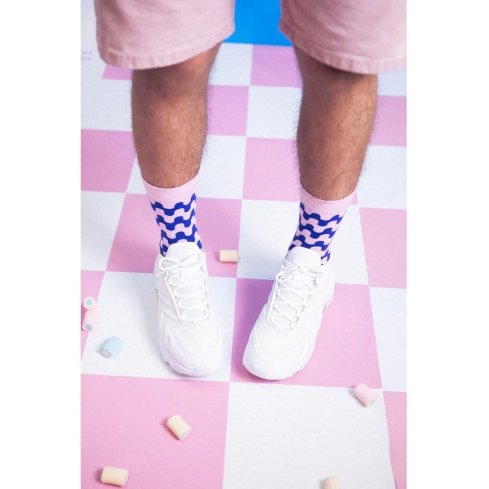 person wearing blue and pink striped socks on a chequered floor 
