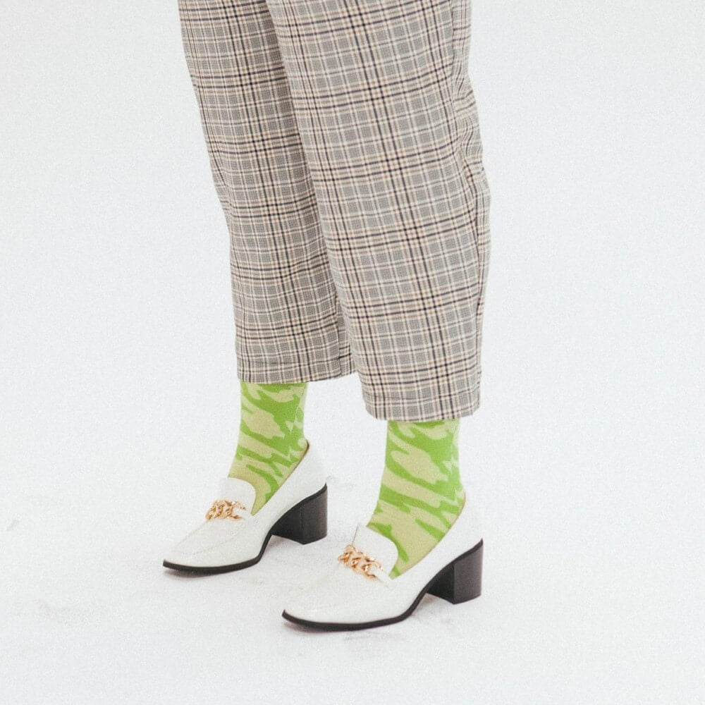 person wearing a pair of Green striped socks with white shoes and check trousers 
 