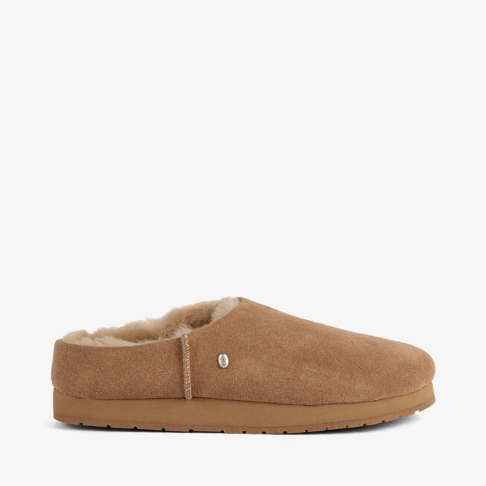 An EMU tan suede slip-on mule slipper with a soft cream wool lining and a tan rubber sole, shown from a side profile on a light gray background.