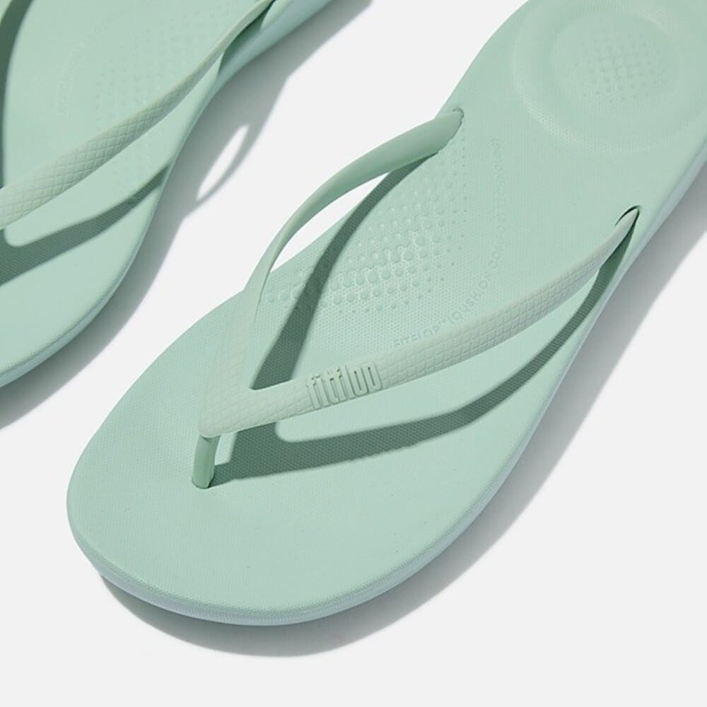 Pair of light green flip-flops on a white background