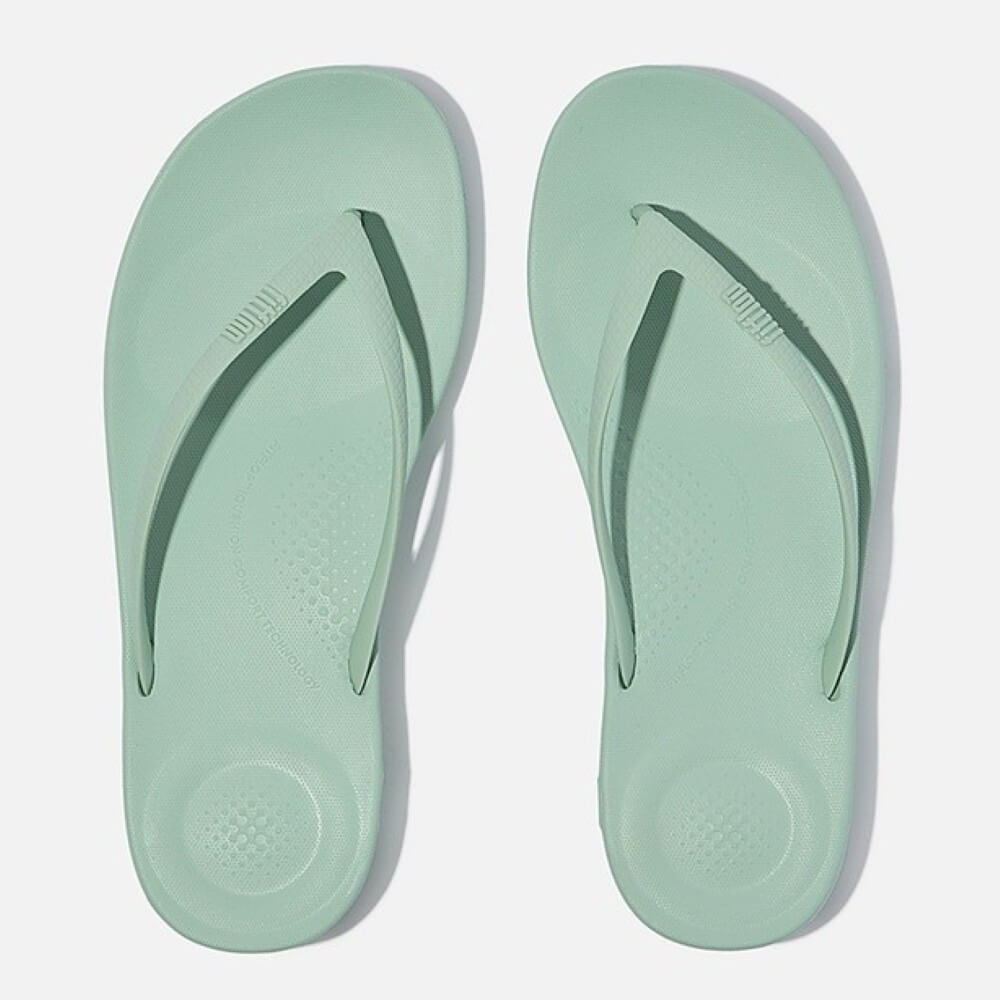 Pair of light green flip-flops on a white background