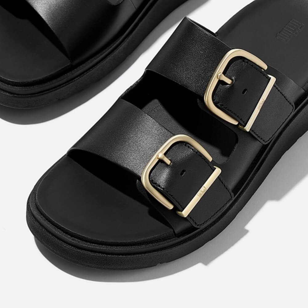 fitflop Black sandal with gold buckles on a white background