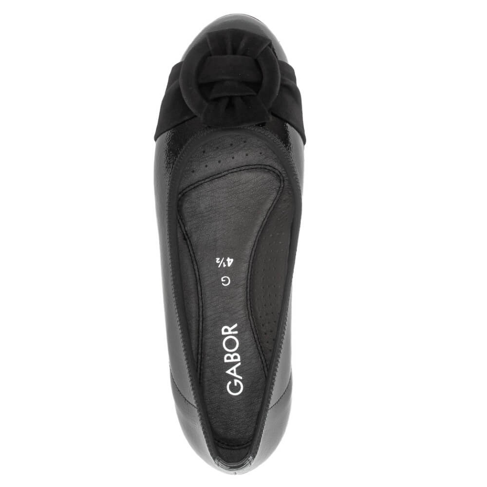 A Gabor black leather flat shoe shown from a top-down view, featuring a decorative black bow at the toe and the brand name 'GABOR' printed in white on the insole.