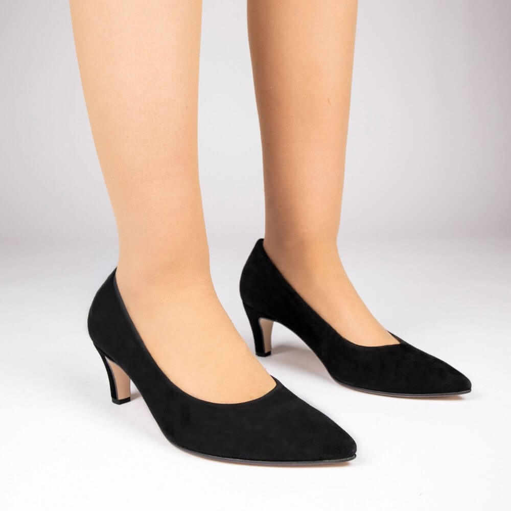 A pair of Gabor black suede pointed-toe pumps with kitten heels, shown on a model's feet against a light grey studio background.