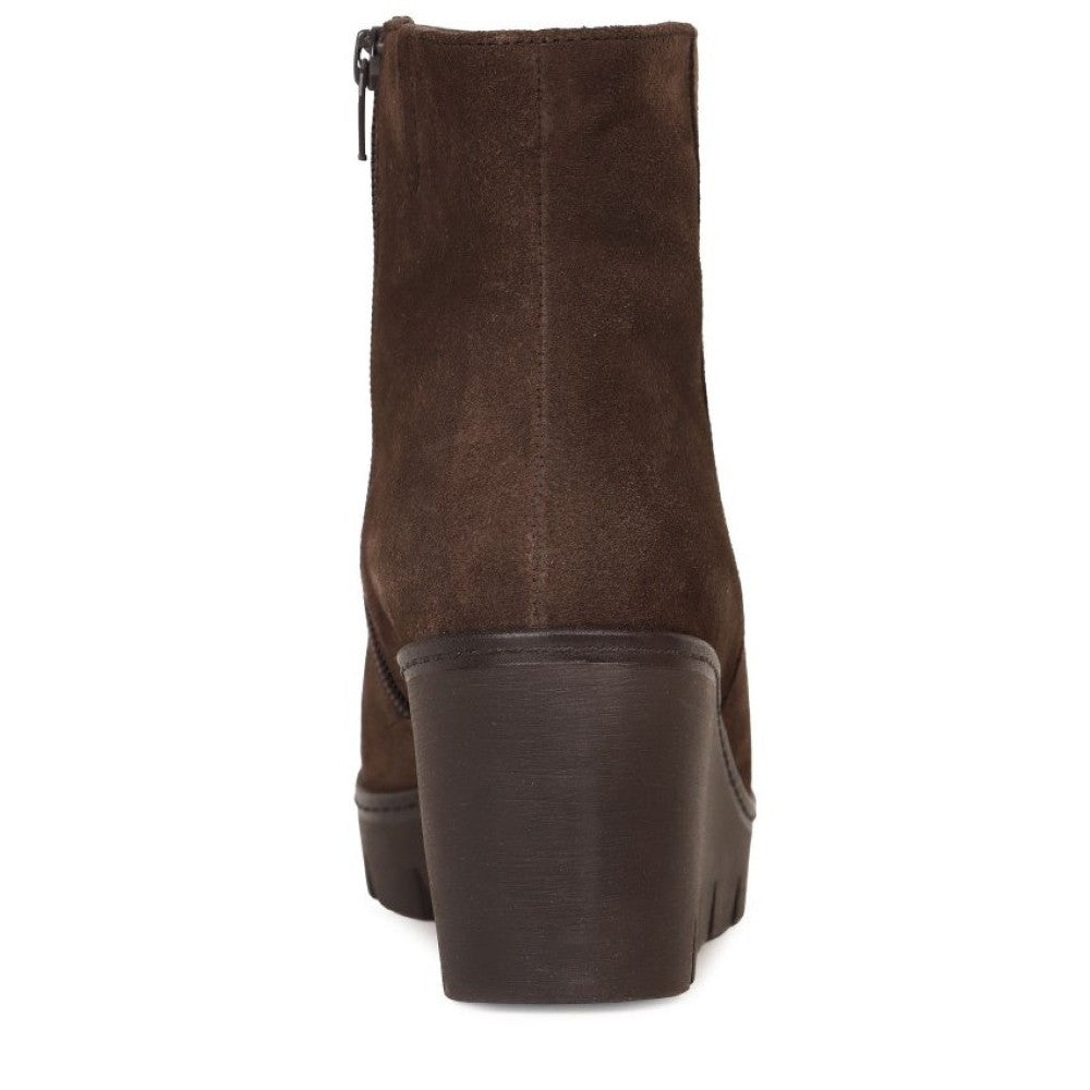 A dark brown suede ankle boot with a chunky block heel and side zipper, shown from a rear three-quarter view on a white background.