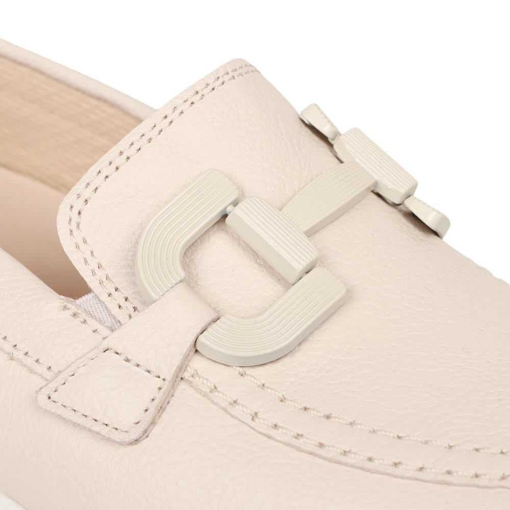 Close-up of a beige shoe with a buckle detail on a white background