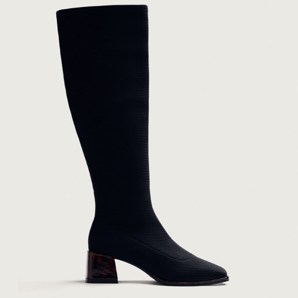 A Gioseppo  black ribbed knee-high boot with a pointed toe and a dark brown tortoiseshell block heel, shown in profile against a light grey background.