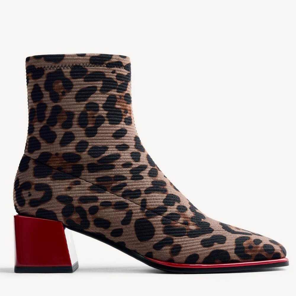 A Gioseppo leopard print ankle boot with a chunky red block heel and a red outsole, shown from a side profile on a light grey background.