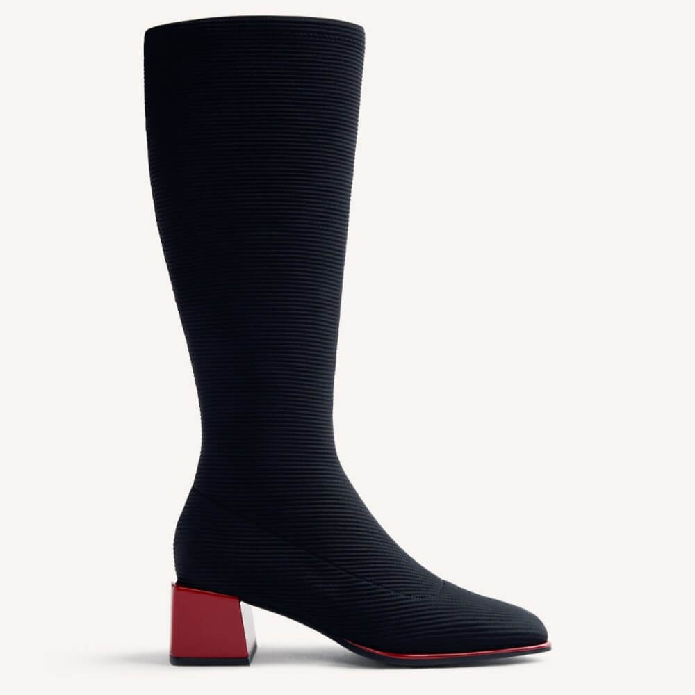 A Gioseppo knee-high ribbed boot in black with a contrasting bright red block heel and red outsole edge, shown in profile against a light gray background.