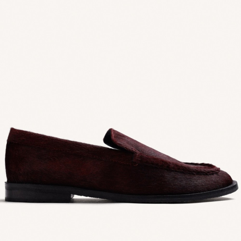A Gioseppo dark burgundy loafer with a textured hair-on-hide finish and a black sole, shown in profile against a plain off-white background.