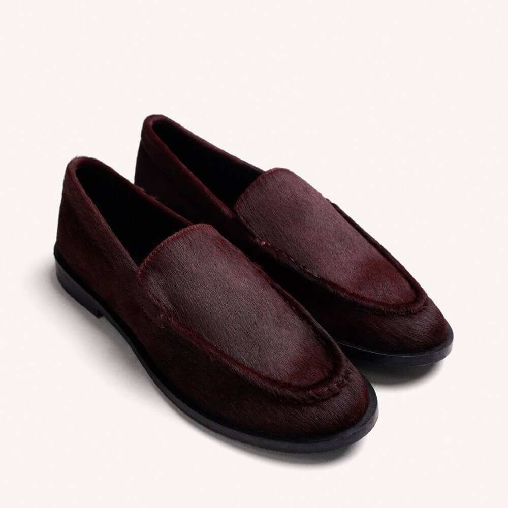 A pair of Gioseppo dark burgundy slip-on loafers with a textured hair-on-hide finish, displayed on a clean off-white background.
