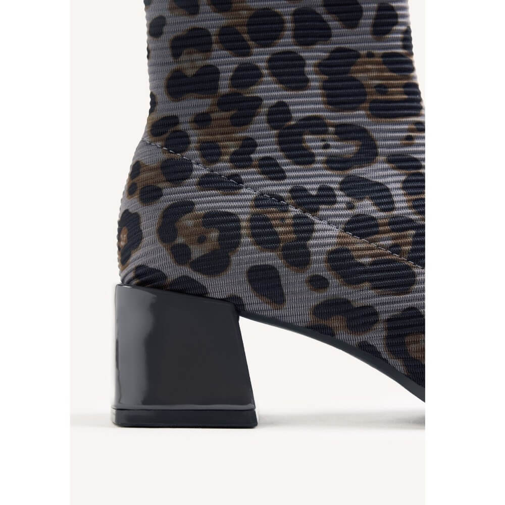 Close-up of a Gioseppo leopard-print ankle boot with a chunky black block heel, showing a grey ribbed fabric upper with black and brown spots.