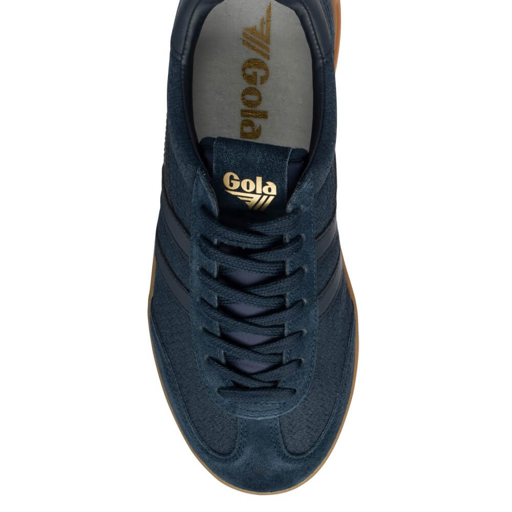 A top-down view of a navy blue suede sneaker with gold 'Gola' branding on the tongue and insole, set against a plain white background.