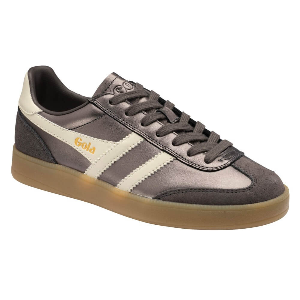 A low-top Adidas Gola sneaker in dark gray suede and leather with cream side stripes, a gold 'Gola' logo, and a translucent gum sole, shown on a plain white background.